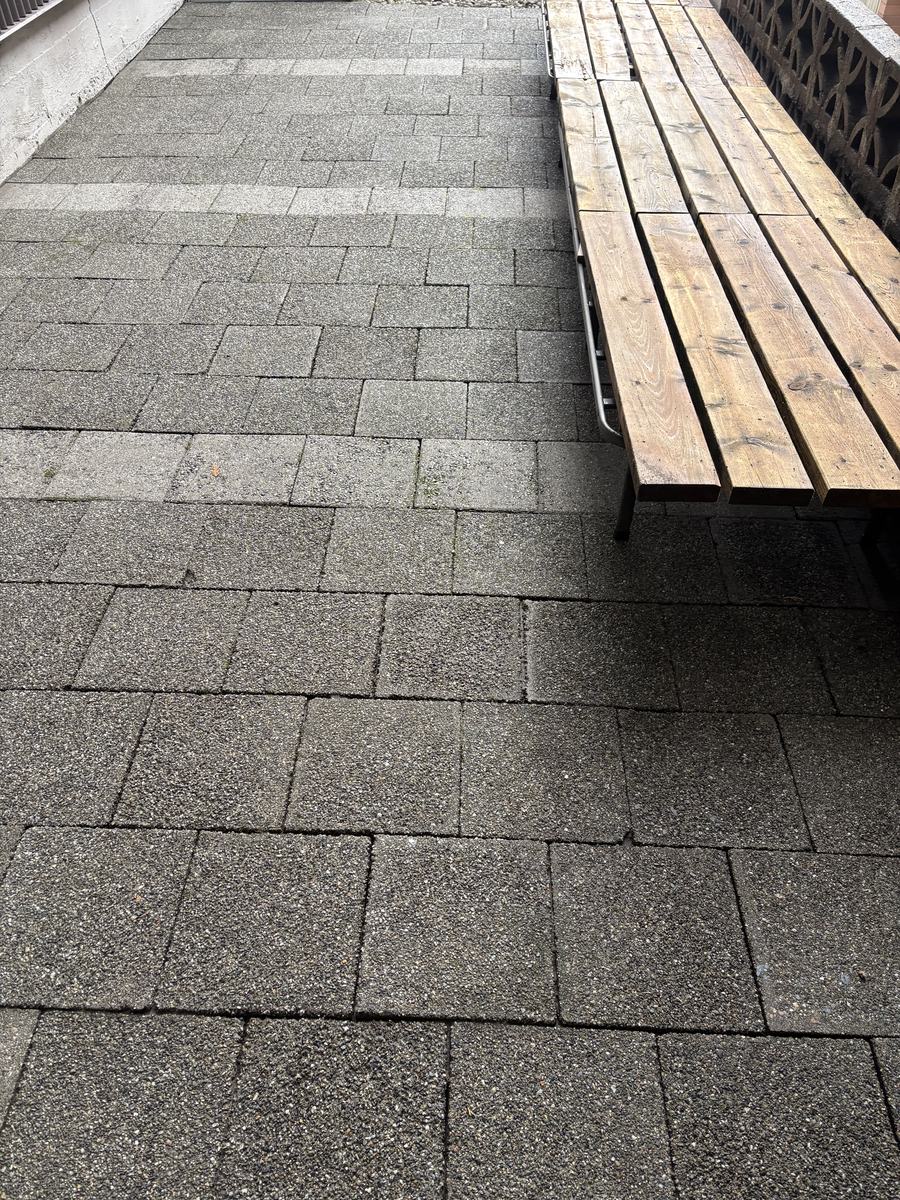The same paver courtyard washed clean, with the wood bench cleaned up beside it
